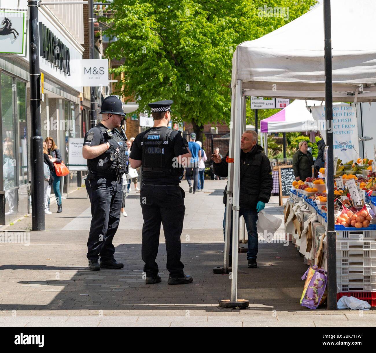 Covid-19 Lockdown Brentwood Essex UK poliziotti Essex chiacchierare con il portastallenti di frutta e verdura in Brentwood High Street Foto Stock