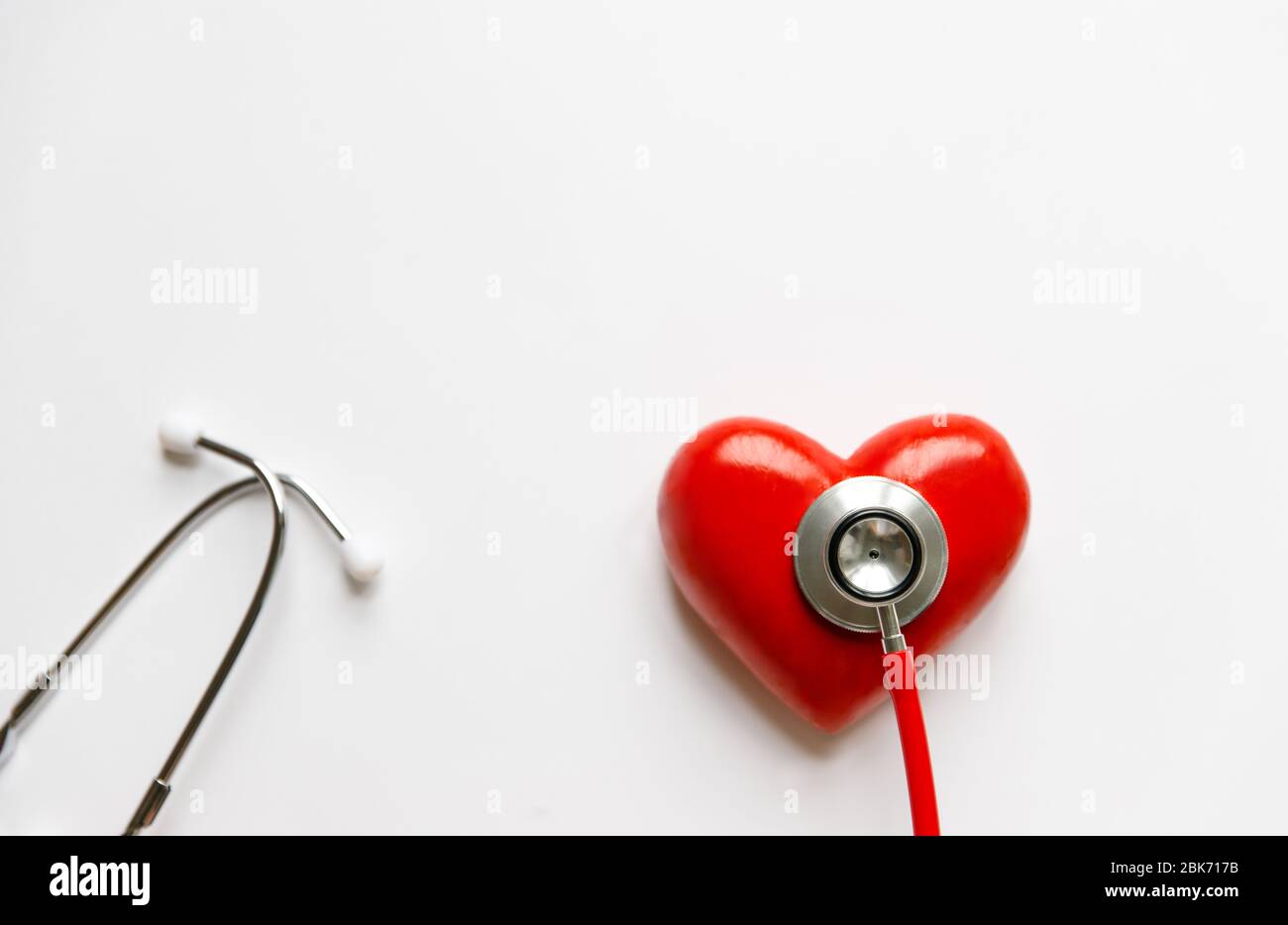 Primo piano dello stetoscopio sul cuore rosso - dispositivo medico diagnostico per l'auscultazione (ascolto) dei suoni provenienti dal cuore, bronchi. Isolato su whi Foto Stock