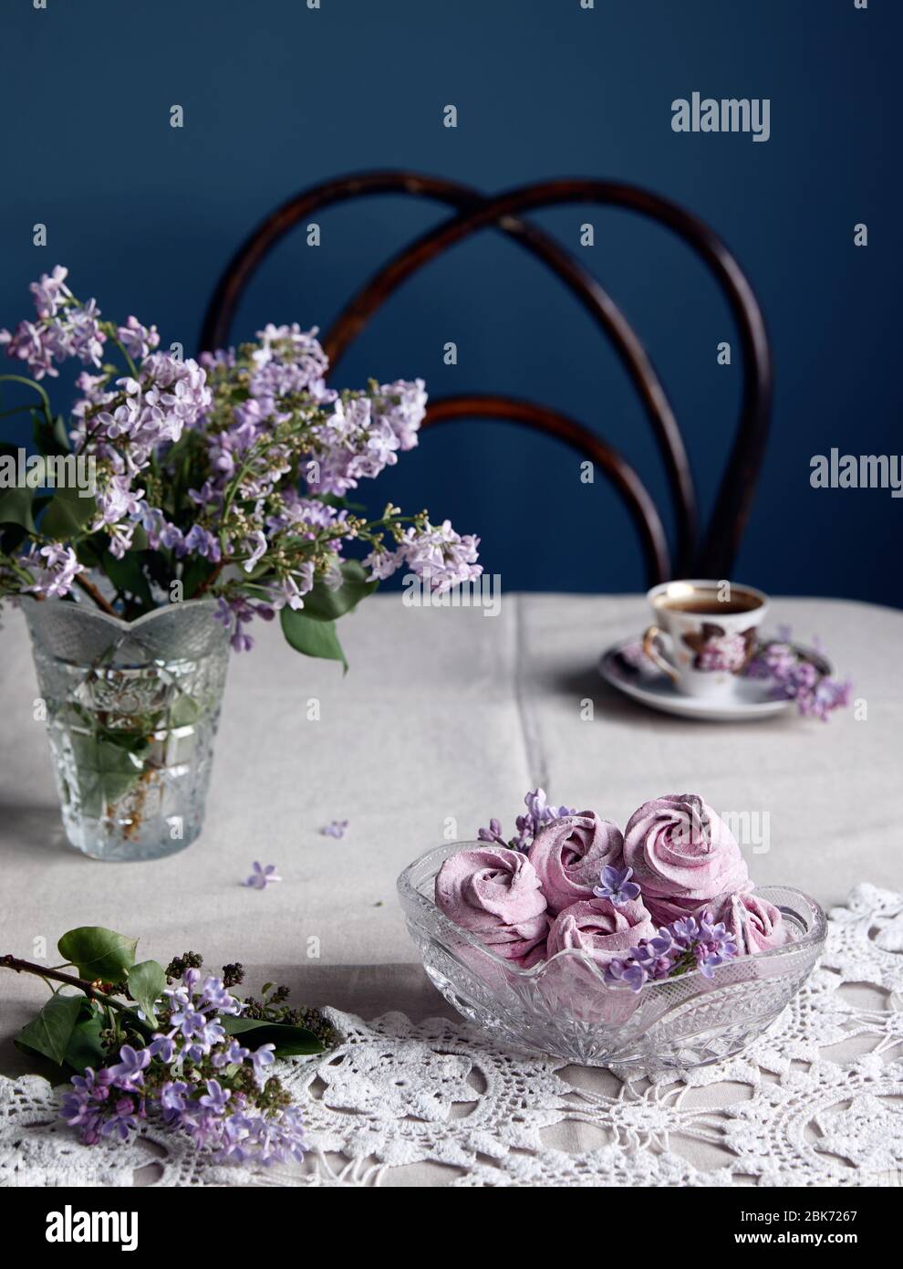 Atmosfera viola dolce fatto in casa Zephyr o Marshmallow da ribes nero vicino ai fiori lilla e tazza di caffè su tela grigia da tavolo e fondente scuro Foto Stock