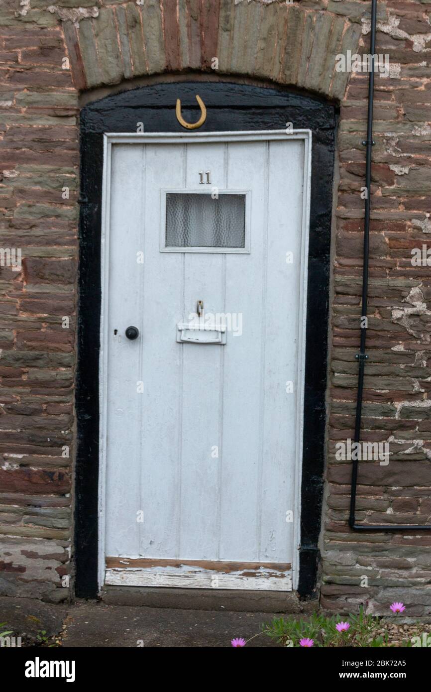 una vista ravvicinata di una porta anteriore bianca con una scarpa da cavallo in alto per una buona fortuna Foto Stock