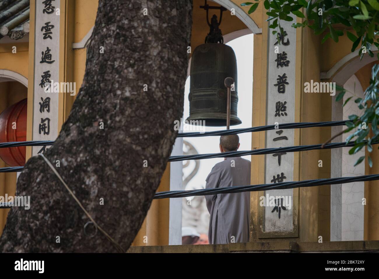 Monaci buddisti ad Hanoi, Vietnam suonano la campana per la preghiera serale Foto Stock