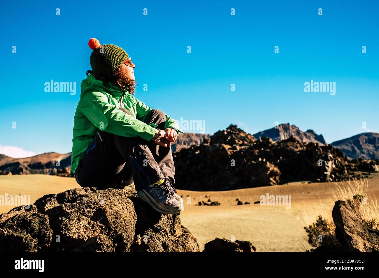 Donna caucasica adulta in sano trekking sport all'aperto e attività di svago - giovane femmina sedersi sulle rocce e godere e riposare in una montagna fre Foto Stock