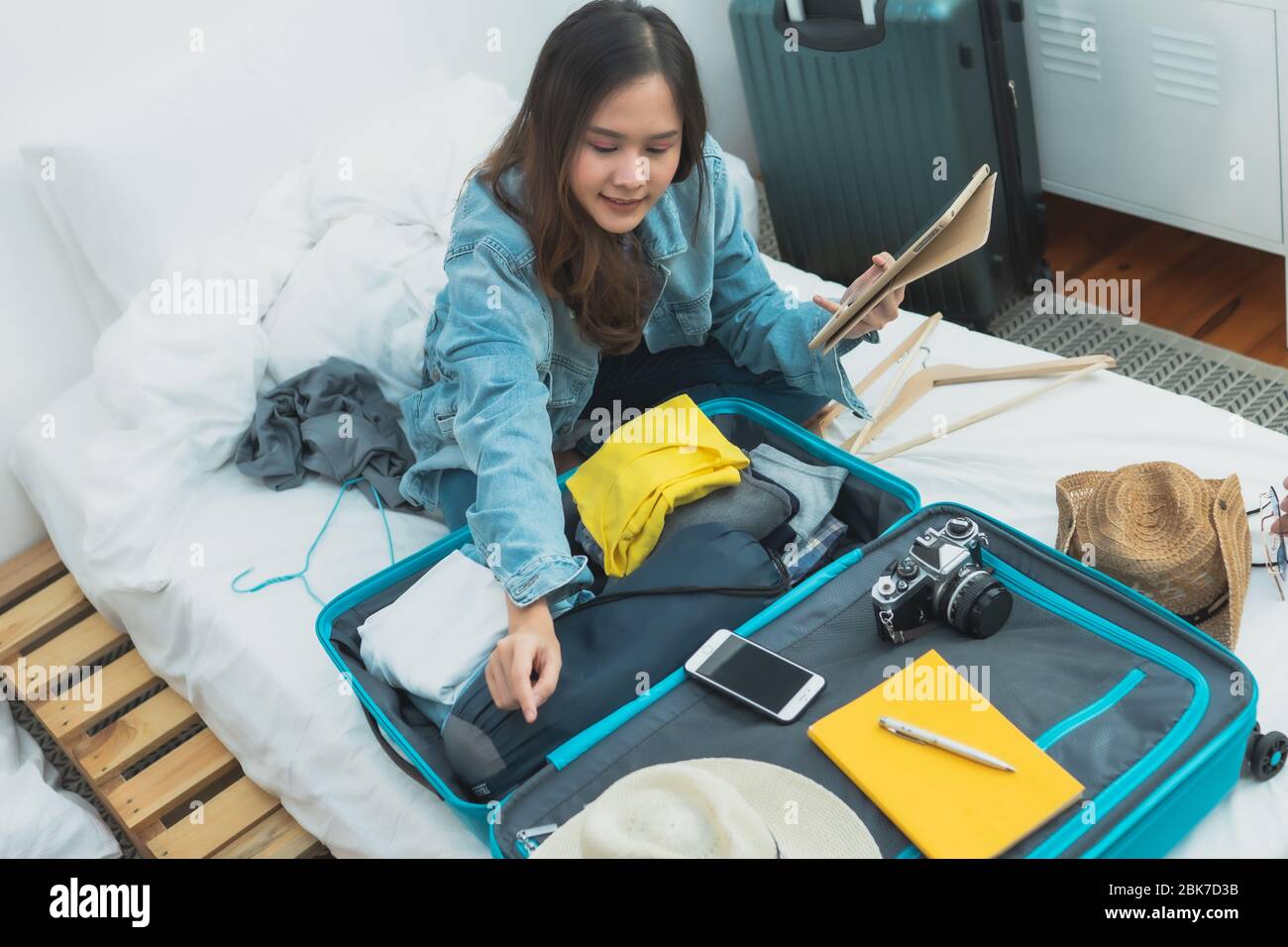 Preparazione e pianificazione del viaggio sul concetto di vacanza, tailandese e Asia donna felice che imballano i vestiti in valigia bagaglio borsa per viaggiare a letto. Foto Stock