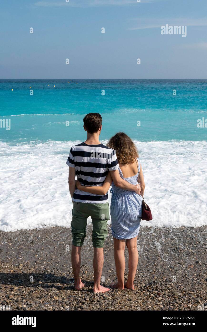 Vista posteriore di una coppia che abbraccia di fronte al mare Mediterraneo a Nizza, Costa Azzurra, Francia, Europa Foto Stock