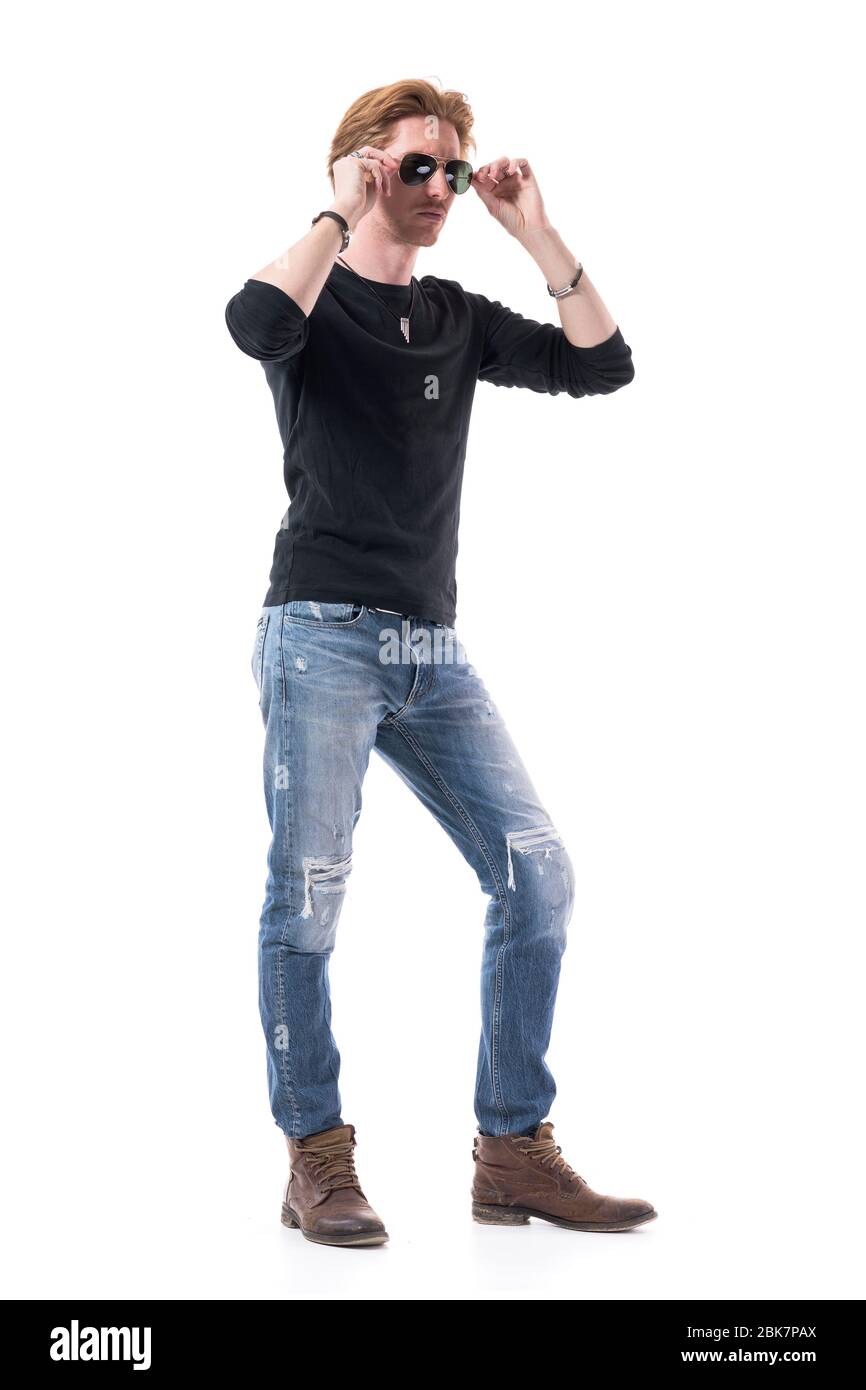 Fresco giovane bell'uomo con capelli rossi che indossano jeans strappati e  camicia nera che prova su occhiali da sole. Corpo intero isolato su sfondo  bianco Foto stock - Alamy