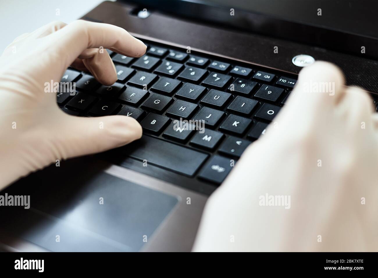Mani nei guanti che digitano sulla tastiera del laptop. Concetto di protezione dai virus Foto Stock