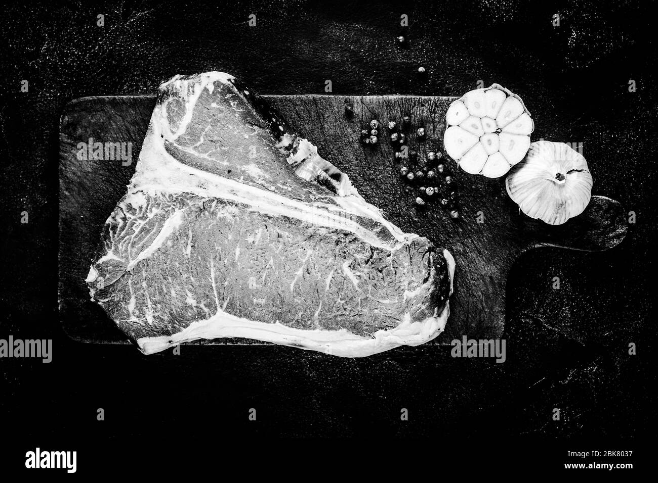 Bistecca premium cruda a T-bone invecchiata a secco su un tavolo da triturazione rustico. Carne di manzo di prima qualità USDA in bianco e nero. Foto Stock