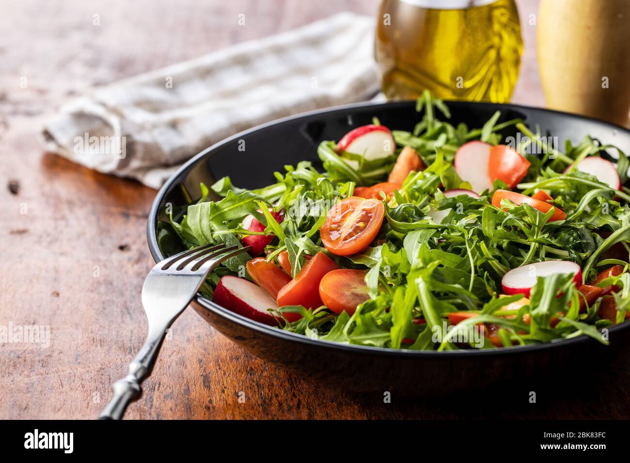Insalata di rucola fresca con ravanelli, pomodori e peperoni rossi sul piatto. Foto Stock