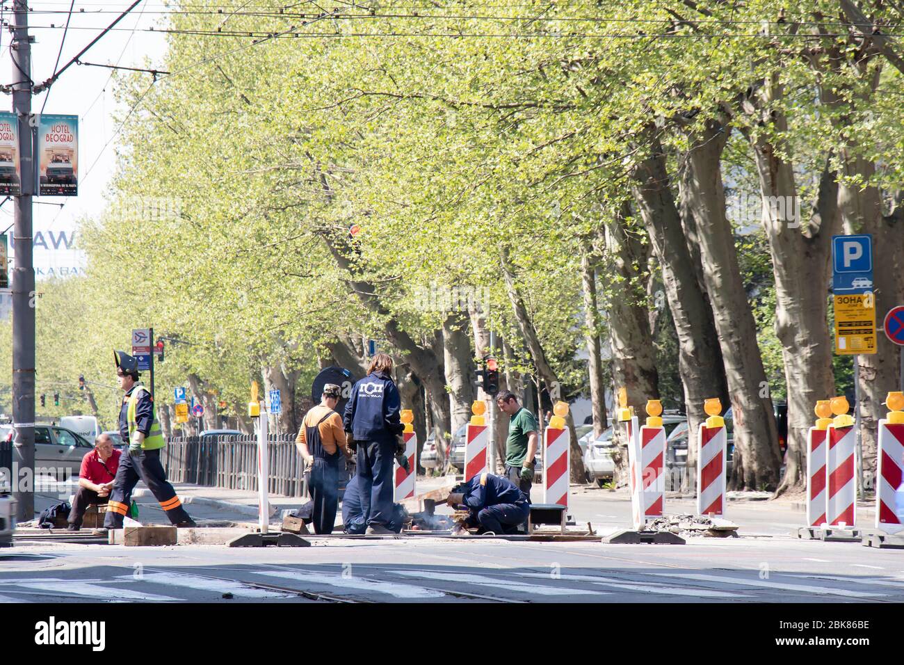 Belgrado, Serbia - 23 aprile 2020: Operai edili che lavorano sul crocevia stradale della città, sostituendo vecchi binari del tram marcio con nuovi una volta, e avvertimenti Foto Stock