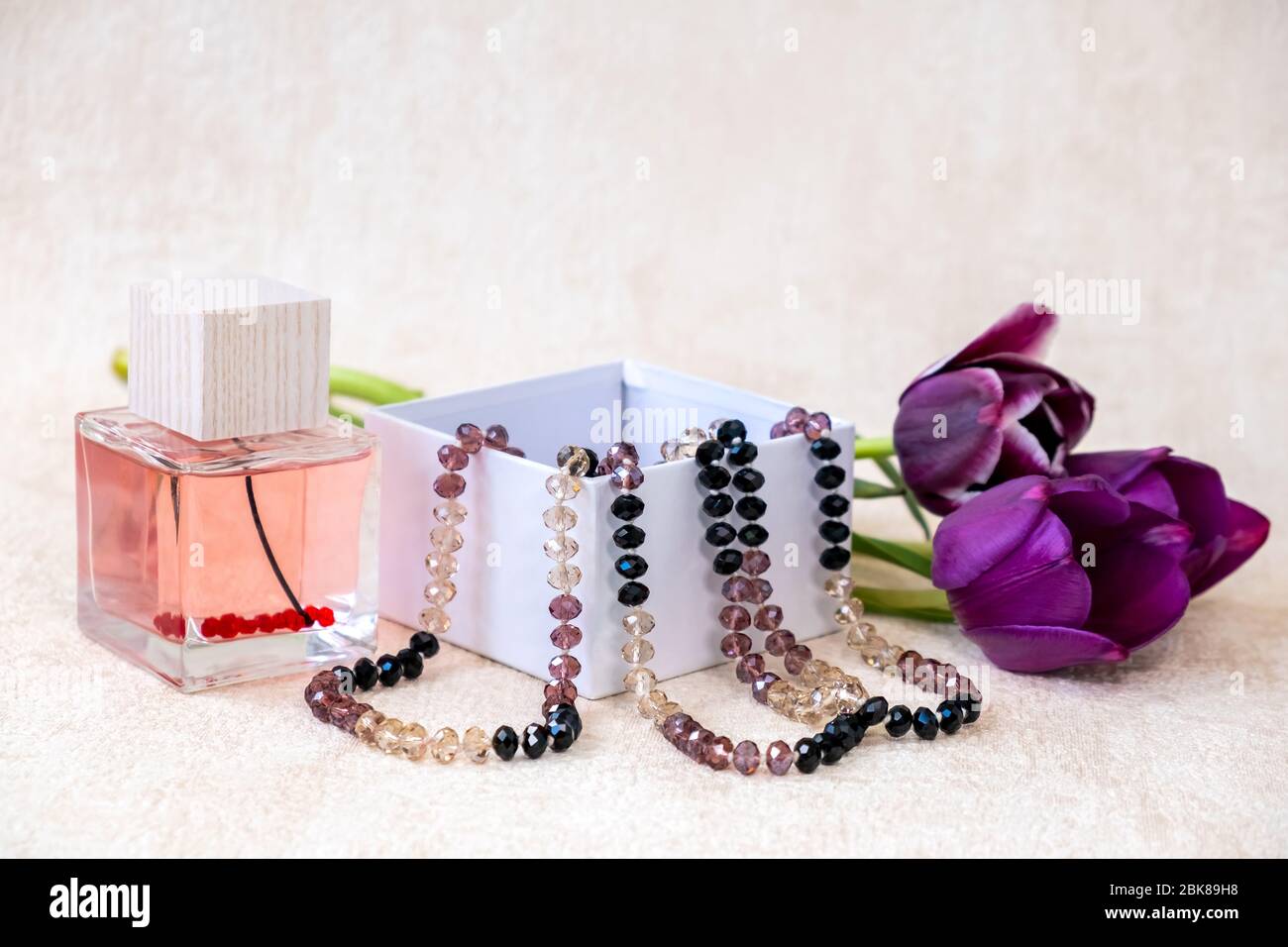 Colori Bordeaux tulipani fiori, perle femmina in una scatola regalo bianca e Eau de Toilette. Un regalo meraviglioso per una donna. Foto Stock
