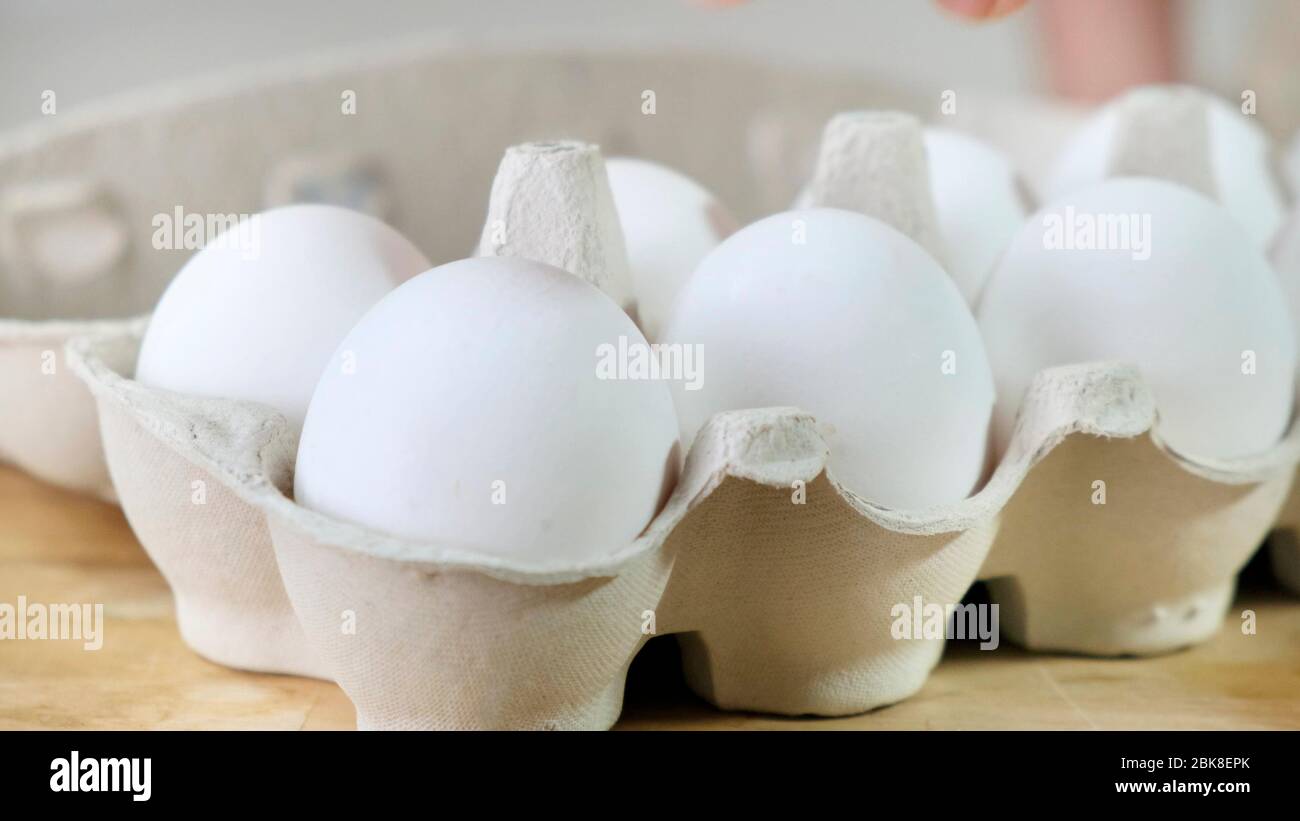 La mano prende una dalle uova imballate in cartone Foto Stock