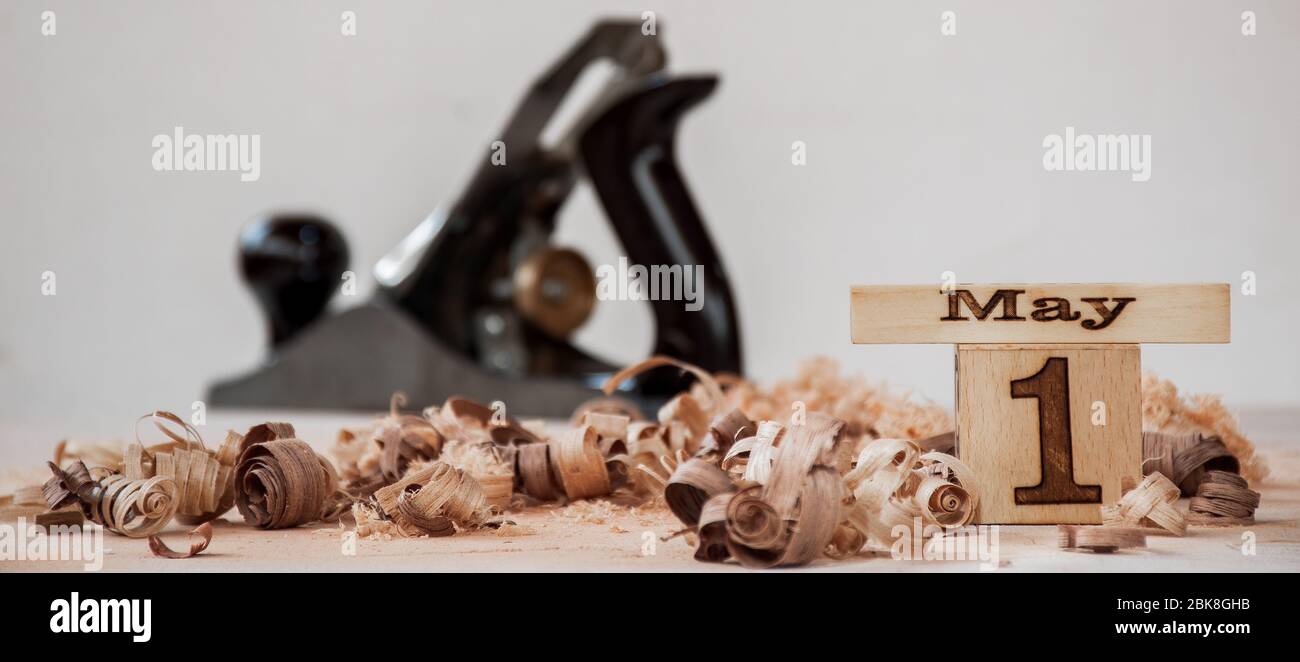 Tema del giorno del lavoro - primo di maggio concetto con cubetti di calendario in legno rimane in trucioli di legno e strumento mano in sfondo sfocato Foto Stock