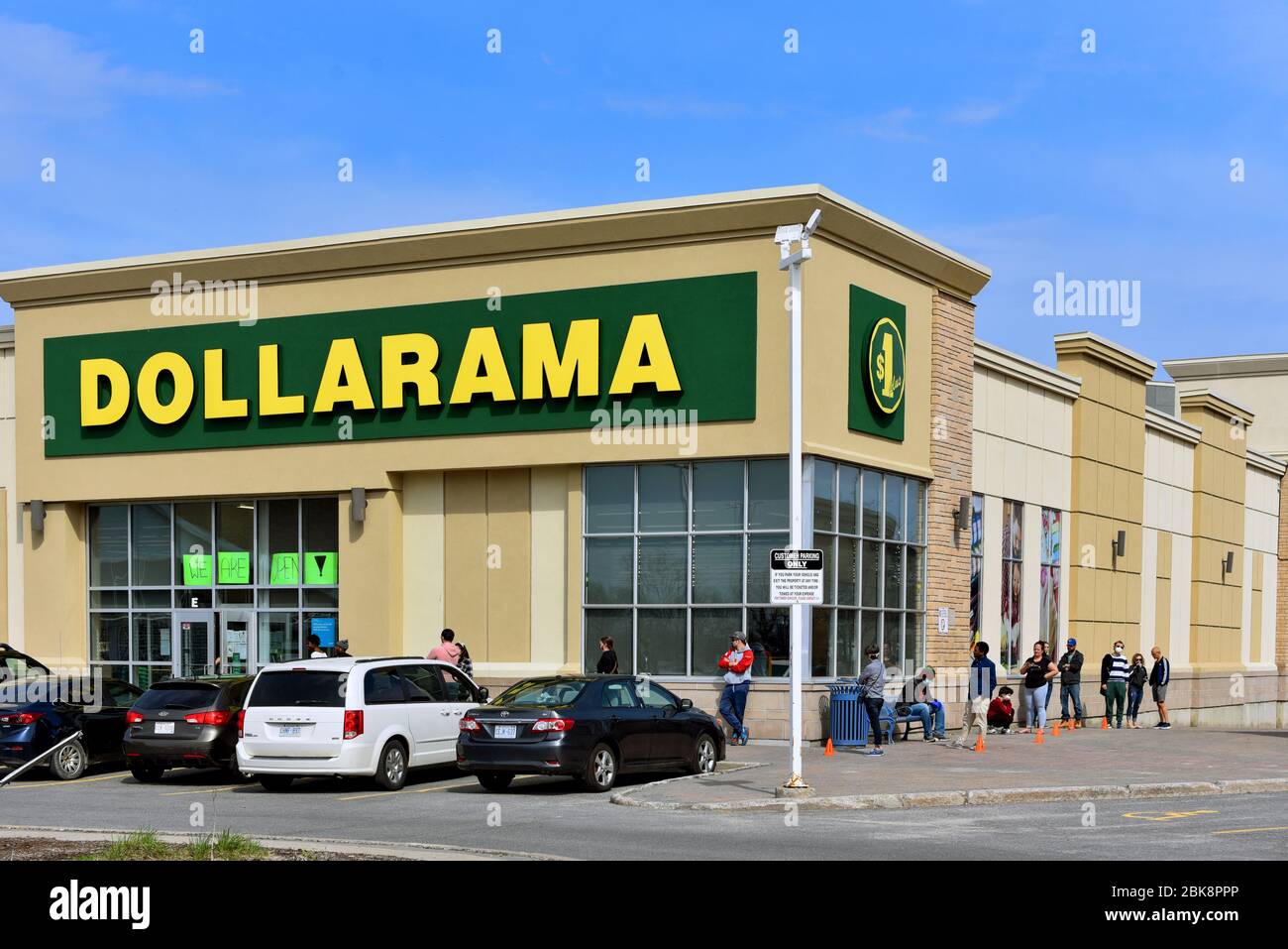 Ottawa, Canada - 2 maggio 2020: I clienti praticano il sociale di distanza mentre aspettano in linea per entrare nel negozio dollaro di Dollarama su Baseline Rd mentre coro Foto Stock