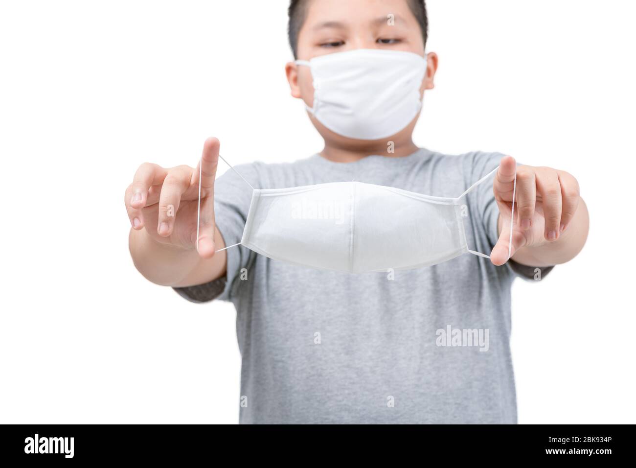 Ragazzo grasso che tiene maschera chirurgica medica in mani isolate su sfondo bianco. Influenza, malattia, misure preventive contro l'infezione da Covid-19. Concetto di Foto Stock