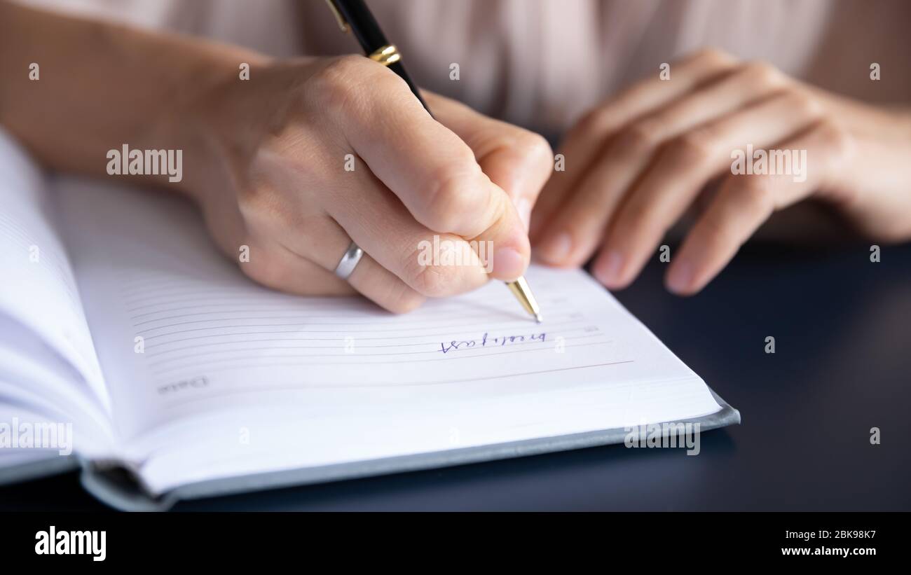 Chiudi la penna di tenuta della mano femminile, scrivendo nel notebook Foto Stock