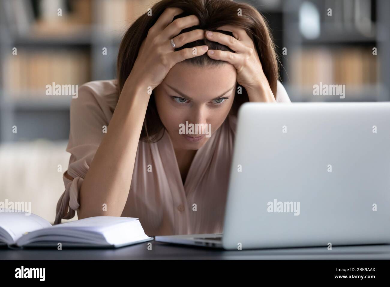 Donna stressata e infelice che guarda lo schermo del notebook, che tocca la testa Foto Stock