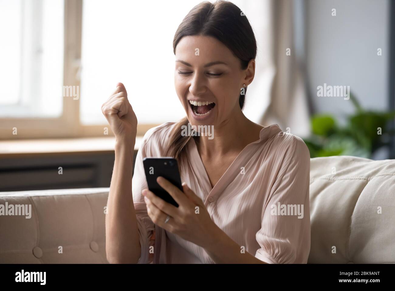 Donna entusiasta che guarda lo schermo del telefono e festeggia la vittoria Foto Stock