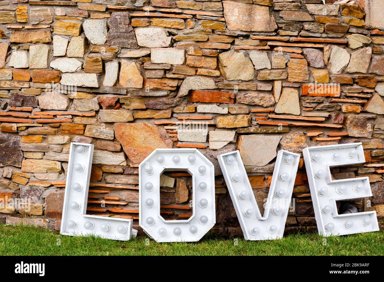 Una parola d'amore vicino al muro di pietra. Area foto in decorazione per matrimoni nel parco Foto Stock