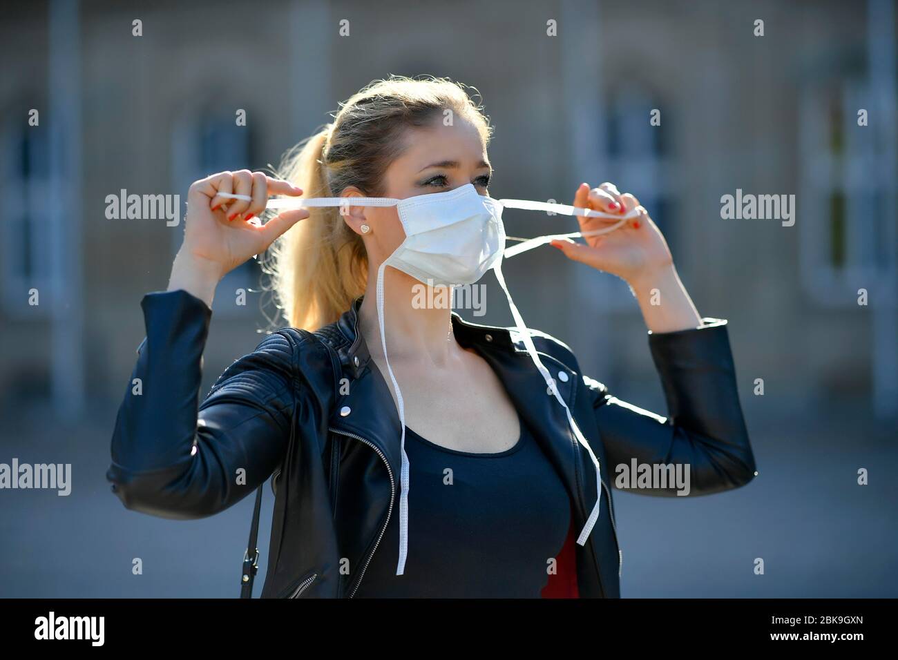 Donna che mette su una maschera facciale, ritratto, crisi corona, Stoccarda, Baden-Wuerttemberg, Germania Foto Stock