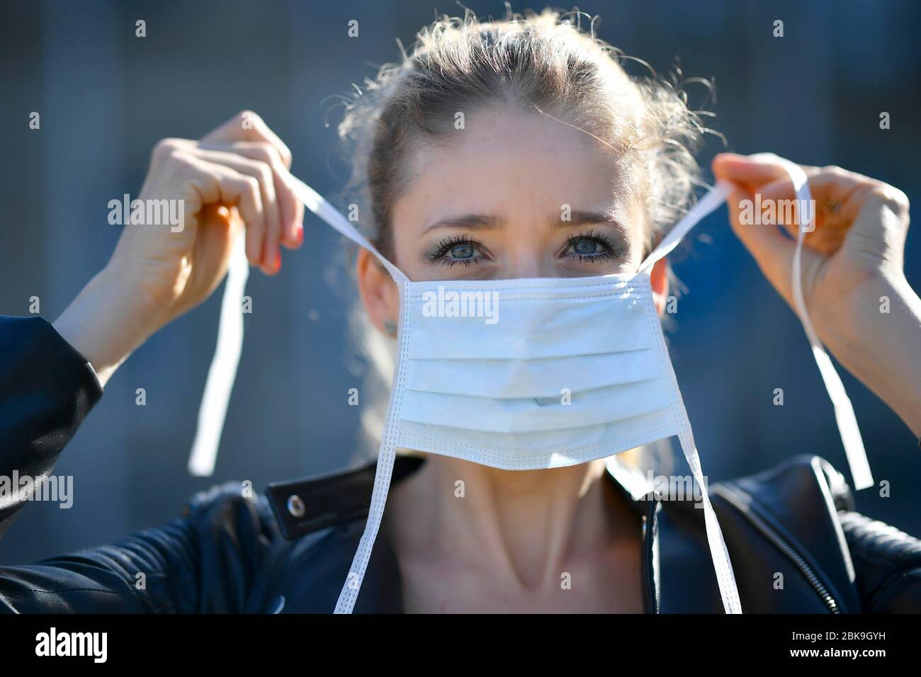 Donna che mette su una maschera facciale, ritratto, crisi corona, Stoccarda, Baden-Wuerttemberg, Germania Foto Stock