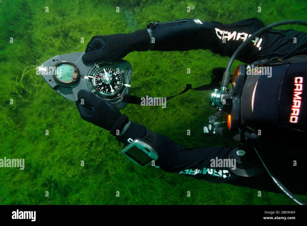 I subacquei in tute asciutte si orientano con la bussola in acque con scarsa visibilità, Echinger Weiher, Eching, alta Baviera, Germania Foto Stock