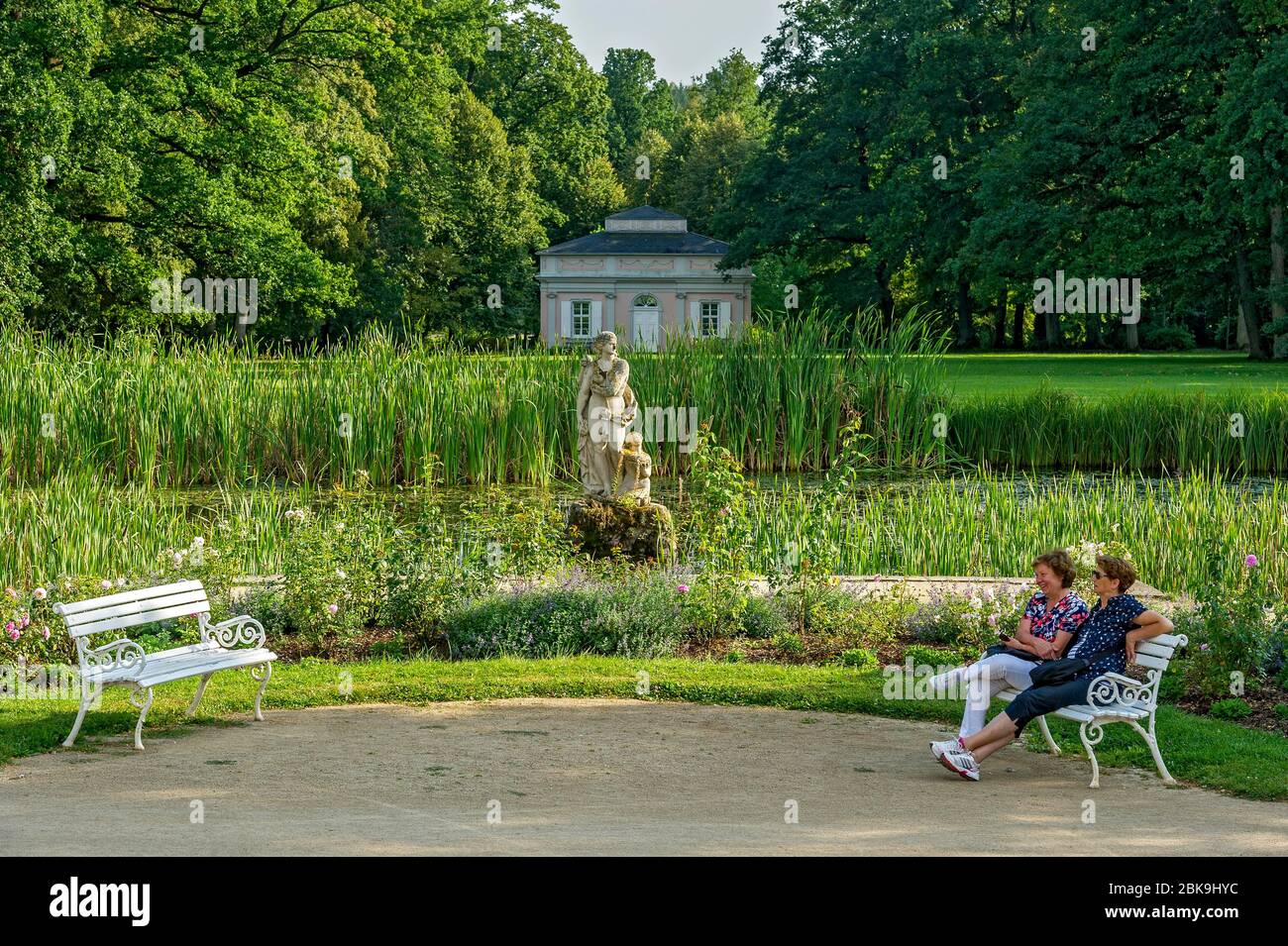 Due donne su panchine, stagno con scultura di Venere, dea dell'amore, di fronte al padiglione cinese, tè casa, parco del castello barocco Fasanerie Foto Stock