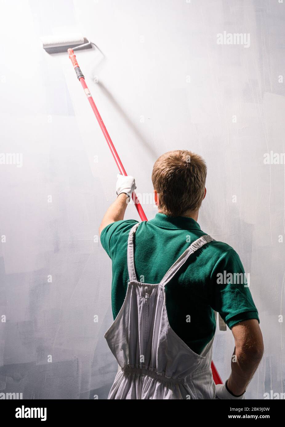 Decoratore maschio che dipinge una parete di colore bianco. Foto Stock