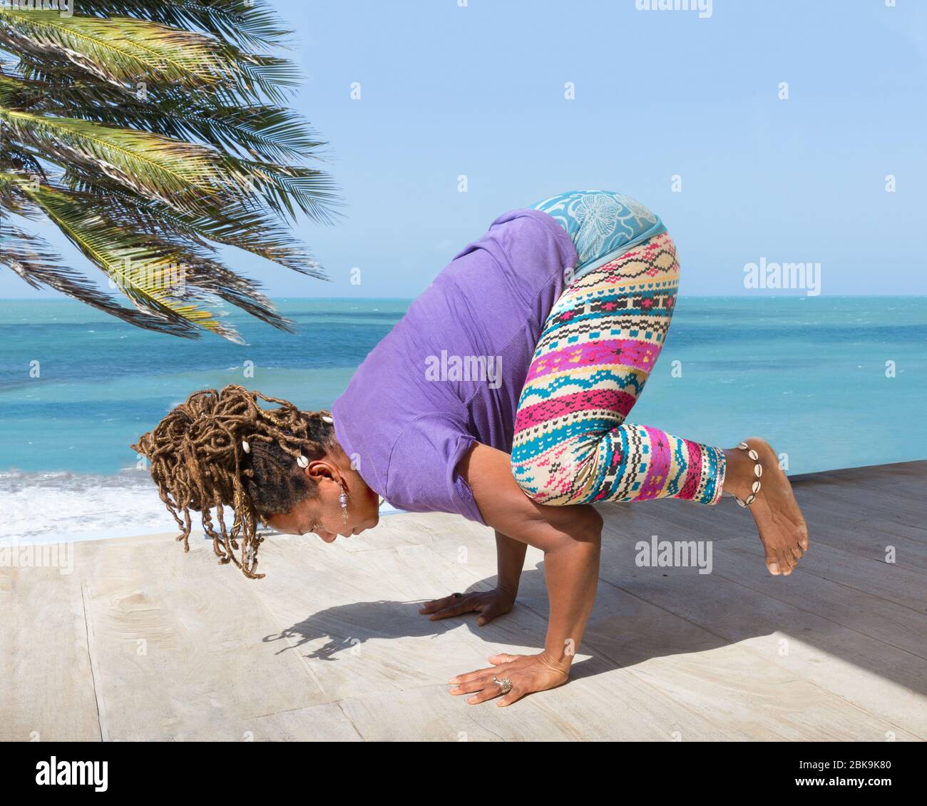 Bella donna nera, africana o carribea che pratica benessere e yoga pose al resort o hotel all'aperto che si affaccia sulla splendida spiaggia e l'oceano. Foto Stock
