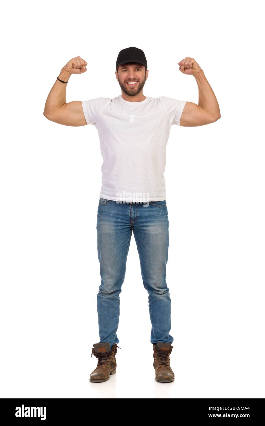 Bell'uomo in jeans, maglietta bianca e cappuccio nero è in piedi, flettendo  i muscoli e sorridendo. Studio di lunghezza completa isolato su bianco Foto  stock - Alamy