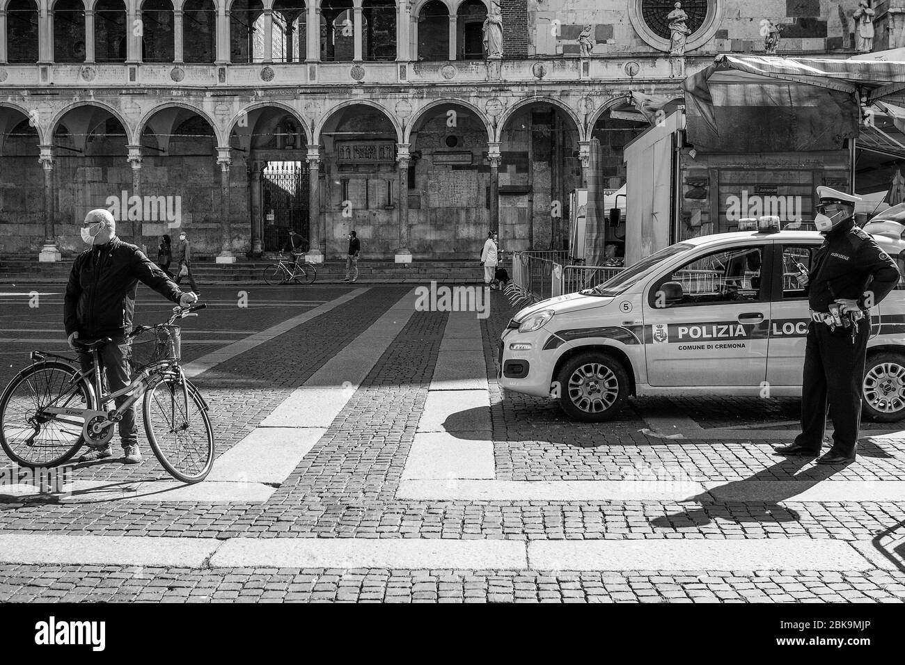 Cremona, Lombardia, Italia - 2 maggio 2020 - poliziotto che controlla la temperatura corporea e l'accesso al mercato alimentare all'aperto nel centro della città Foto Stock