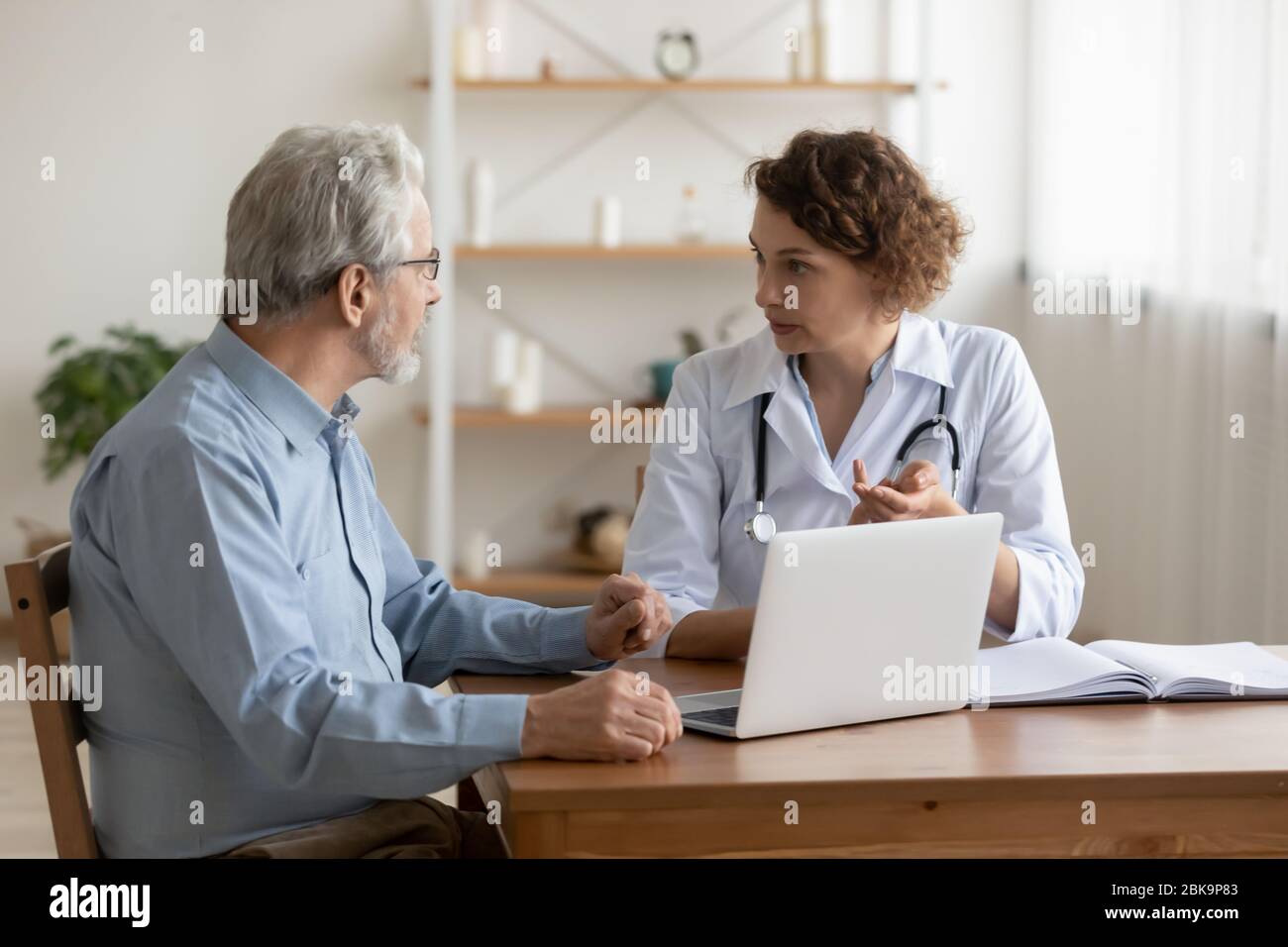 Medico professionale femminile che spiega il trattamento della malattia geriatrica al paziente anziano Foto Stock