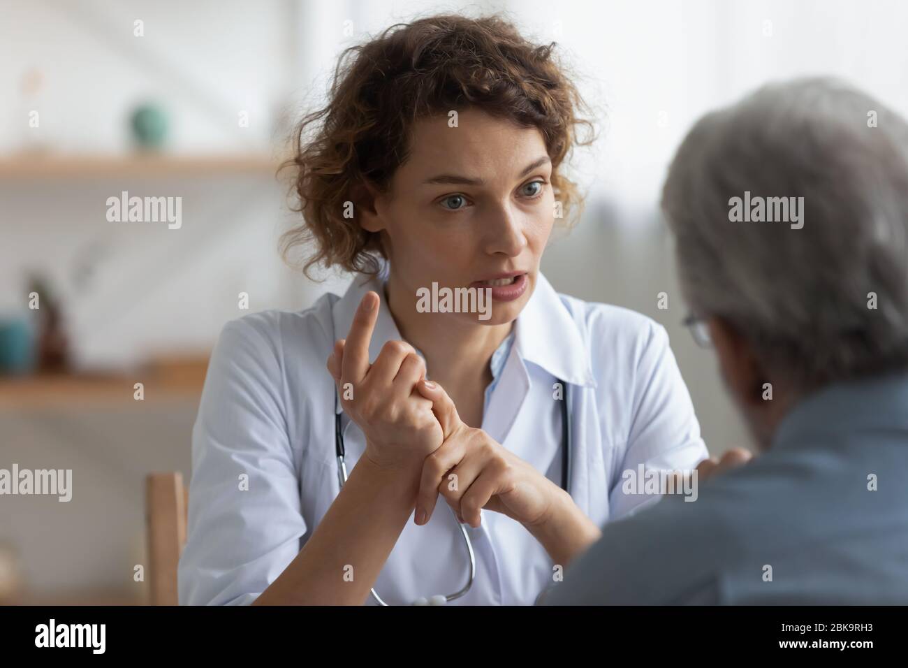 Medico femminile che parla con il paziente anziano in visita in ospedale Foto Stock