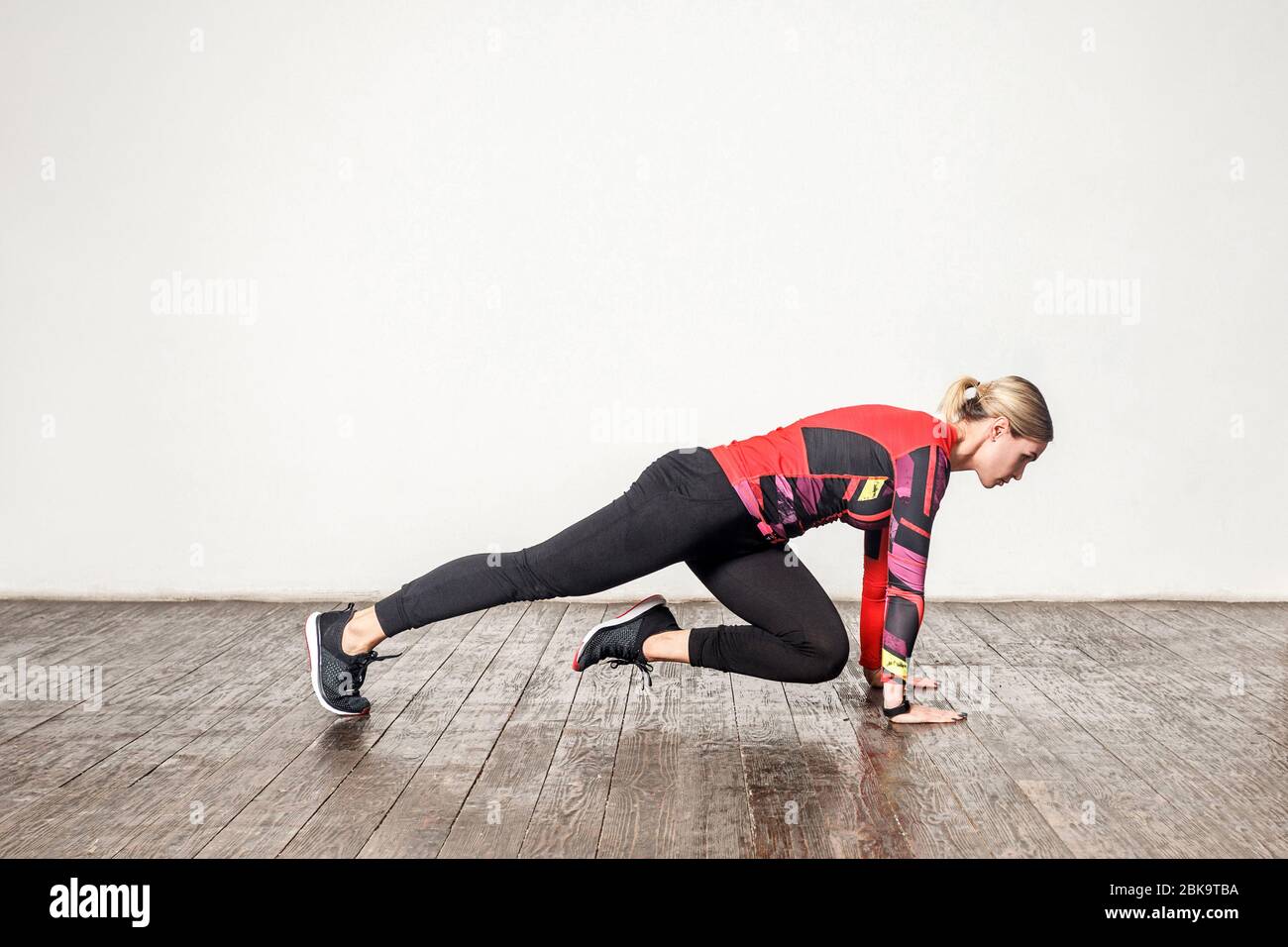 Vista laterale della donna atletica sottile in stretto abbigliamento sportivo pratica yoga, facendo asse gamba piegata, flessibilità di allenamento, forza muscolare. Assistenza sanitaria, sport Foto Stock