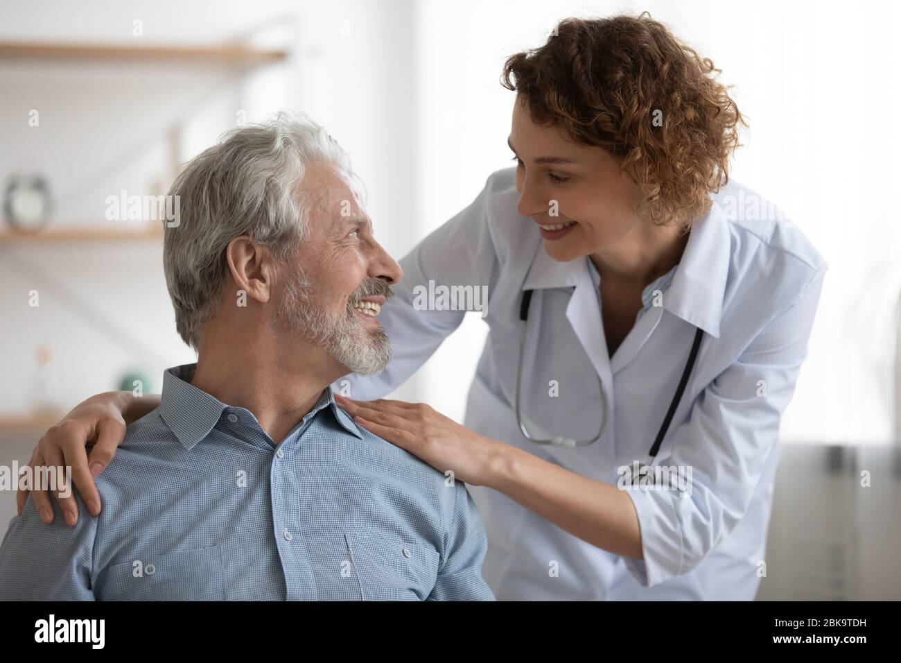 Gentile medico femminile sorridente che abbraccia incoraggiando un paziente maschile felice Foto Stock