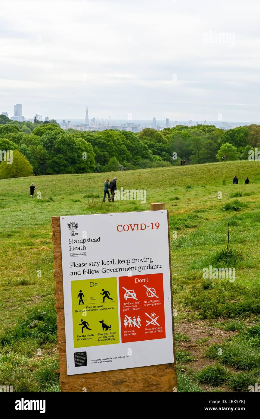 Hampstead Heath e London skyline, con istruzioni illustrate durante la pandemia di Covid-19. La gente cammina e corre osservando le distanze sociali. Foto Stock