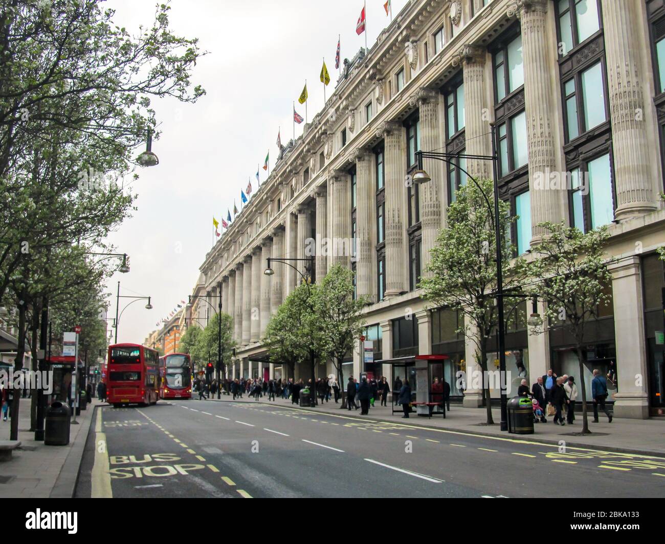 Oxford Street passando davanti al famoso Selfridge Department Store con alberi a gemma lungo i lati della strada, fotografato in una mattina di primavera Foto Stock