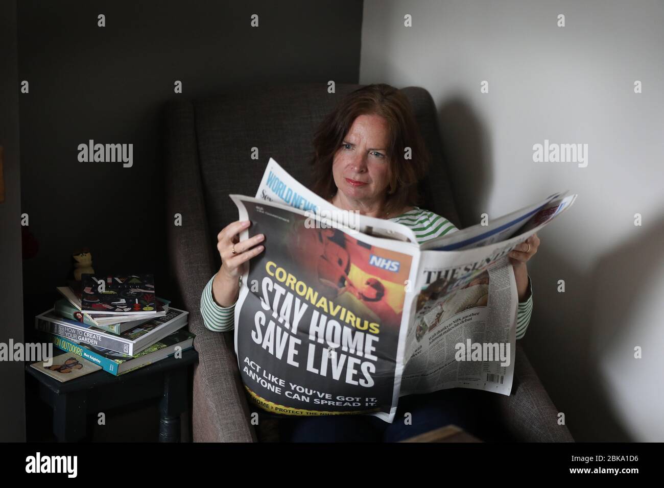 Una donna che legge il giornale del Sunday Times a casa durante il Lockdown a causa del Pandemic Coronavirus che spazzano il mondo. Foto Stock