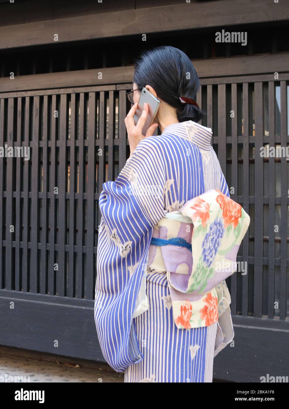 Donna giapponese in kimono che parla sul suo smartphone mentre cammina Foto Stock