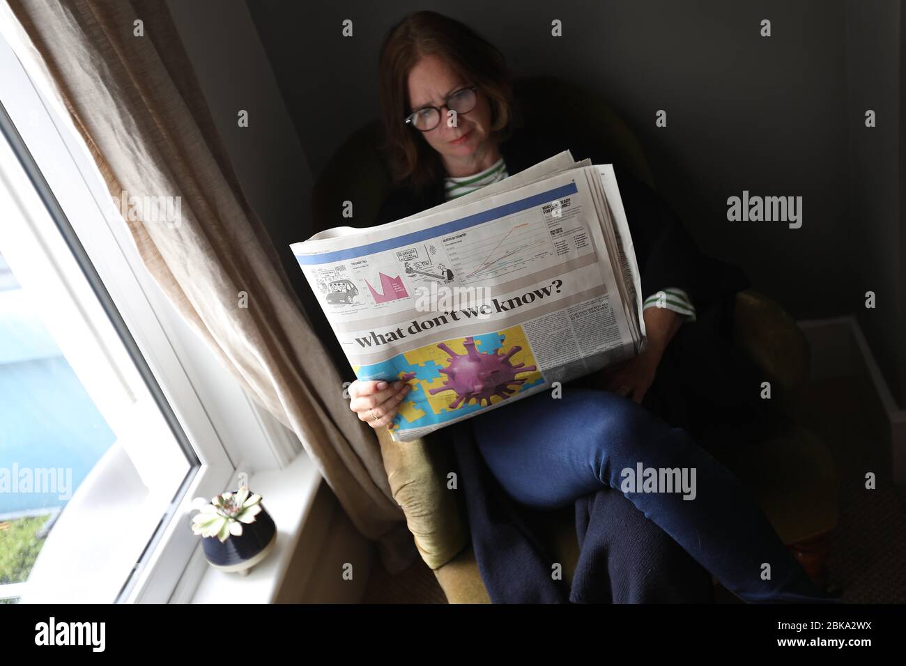 Una donna che legge il giornale del Sunday Times a casa durante il Lockdown a causa del Pandemic Coronavirus che spazzano il mondo. Foto Stock