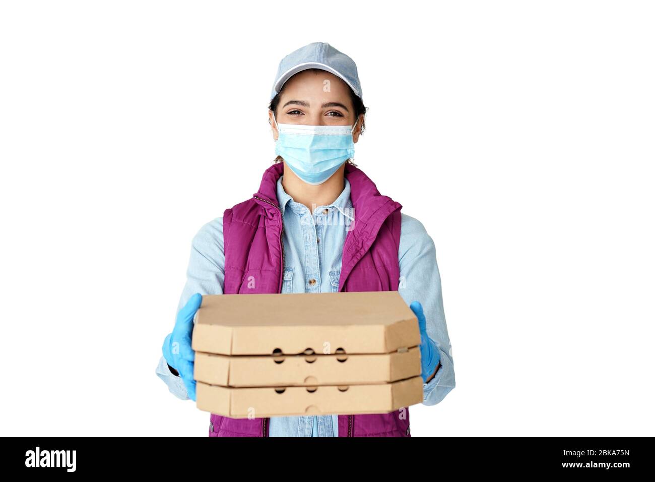 Donna ispanica corriere indossa guanti maschera tenendo scatole pizza isolato su bianco. Foto Stock
