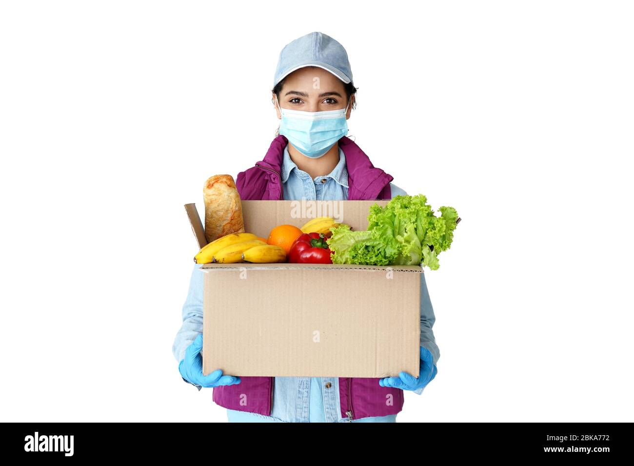 Il corriere della donna ispanica indossa la maschera e i guanti che tengono la scatola di consegna del cibo. Foto Stock