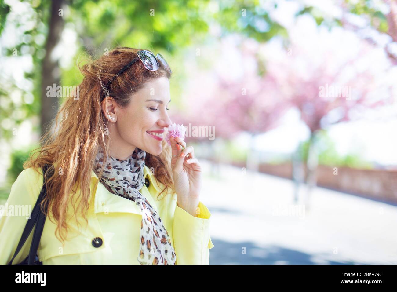 Giovane allegra donna che odora ciliegia fioritura nel parco in primavera Foto Stock