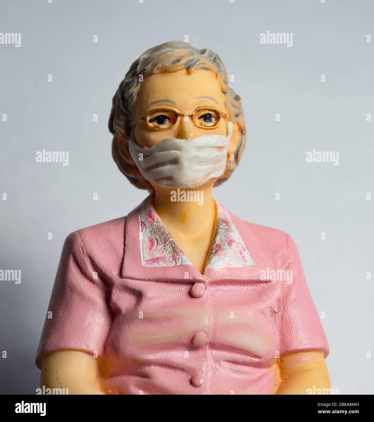 Donna pensionato che indossa una maschera facciale, covid-19, protezione contro il virus della corona, figurine miniaturizzate Foto Stock