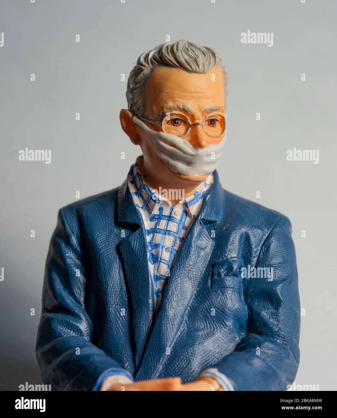 Pensionato maschio con maschera facciale, covid-19, protezione contro il virus della corona, figurine miniaturizzate Foto Stock