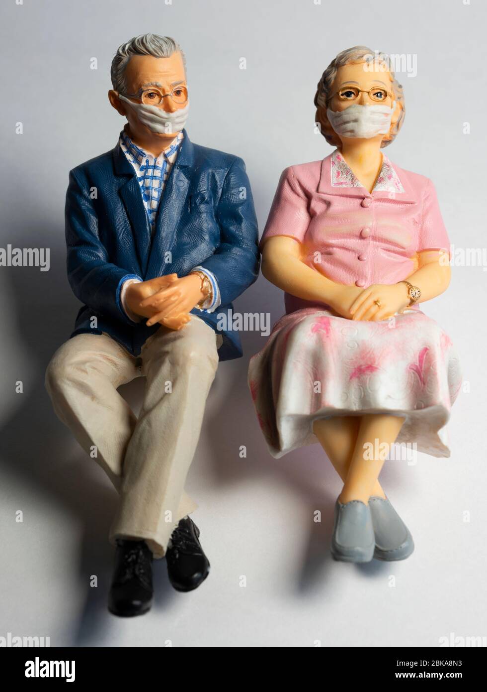 Coppia di pensionati che indossano maschere facciali, covid-19, protezione contro il virus corona, figurine miniaturizzate Foto Stock