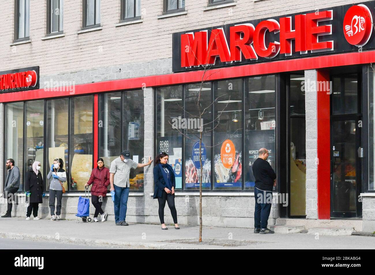 Persone che si allineano di fronte al supermercato, pur rispettando le distanze sociali nel quartiere di lavoro degli immigrati di Park Extension a Montreal Canada Foto Stock