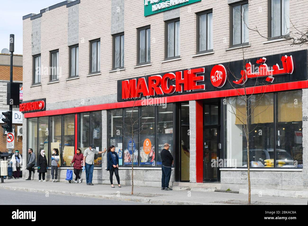 Persone che si allineano di fronte al supermercato, pur rispettando le distanze sociali nel quartiere di lavoro degli immigrati di Park Extension a Montreal Canada Foto Stock
