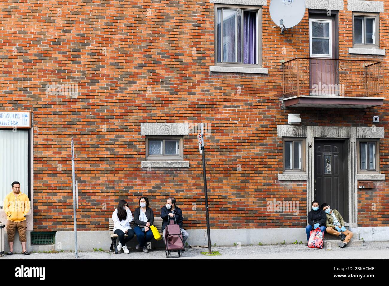 Persone in attesa dell'autobus durante il Covid 19 Pandemic, a Park Extension, un quartiere immigrato di Montreal Canada Foto Stock
