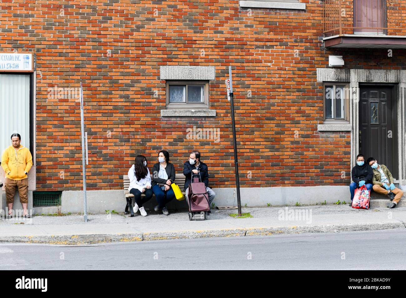 Persone in attesa dell'autobus durante il Covid 19 Pandemic, a Park Extension, un quartiere immigrato di Montreal Canada Foto Stock
