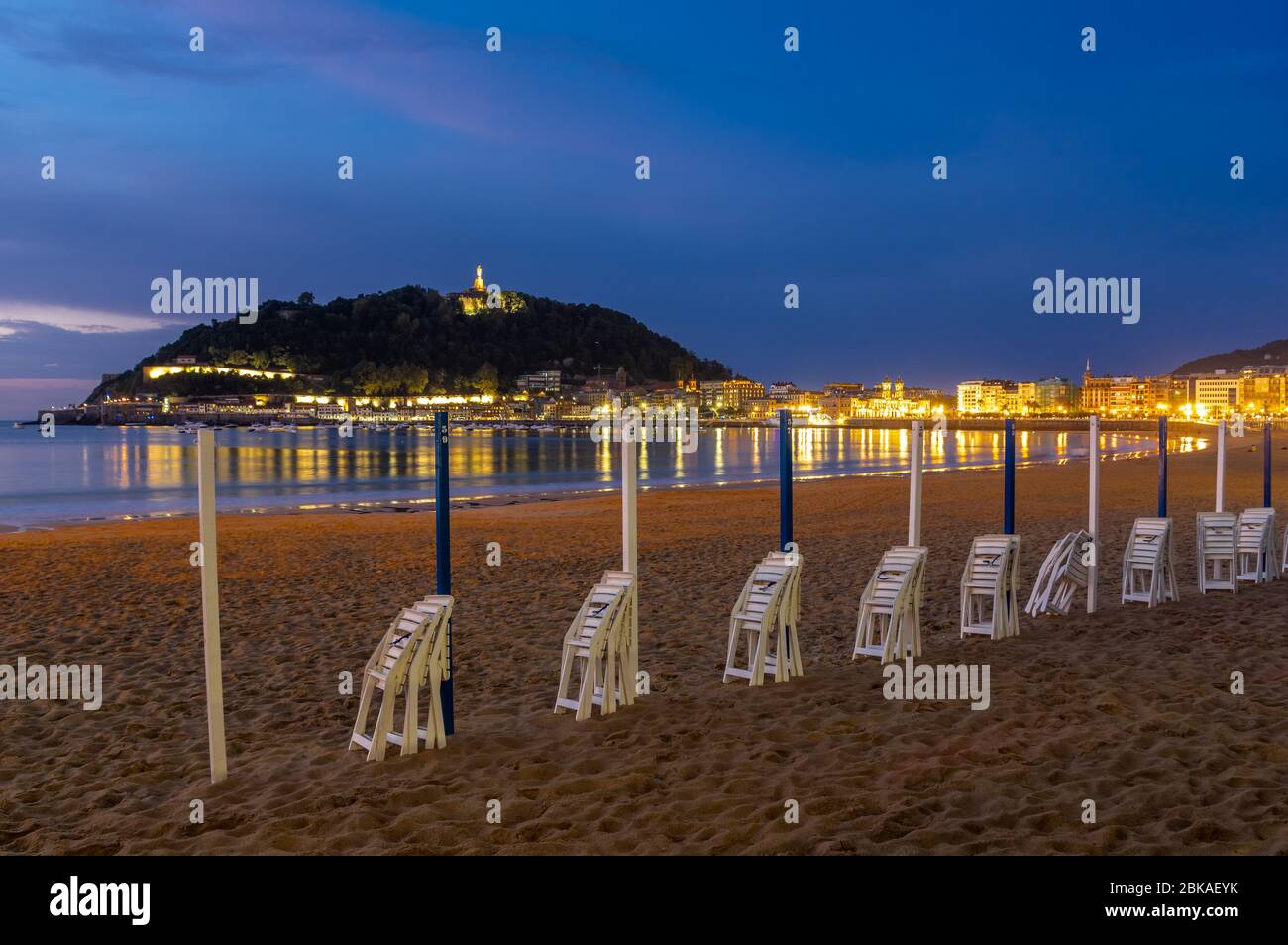 Le luci di San Sebastián aka Donostia che si riflettono nelle acque della Baia di Biskay nel Paese Basco nella parte settentrionale della Spagna, in serata Foto Stock